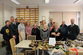 Trofea oraz akcesoria myśliwskie na tle grupy osób